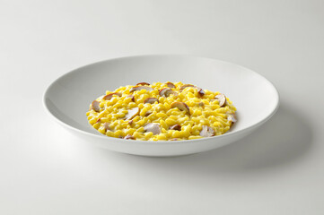 White bowl with yellow risotto with porcini mushrooms saffron