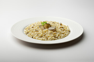 White dinner plate with risotto and slices of black truffle