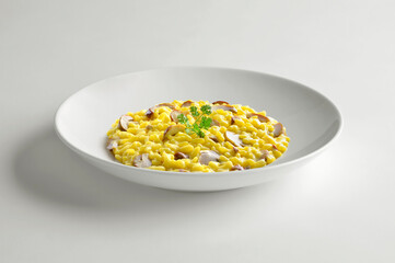 Yellow risotto with saffron, porcini mushrooms and parsley in white bowl