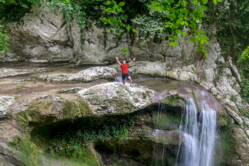 A male traveler admires waterfalls on the Agura River in Sochi