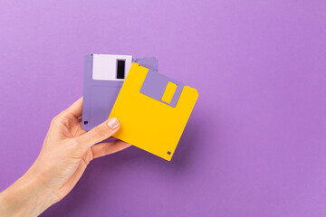 Hand holding floppy disk on color background, technology concept.