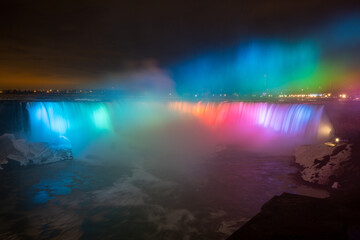 Night illumination on Horseshoe Falls at Niagara Falls Canada are pouring water through frozen landscape at winter