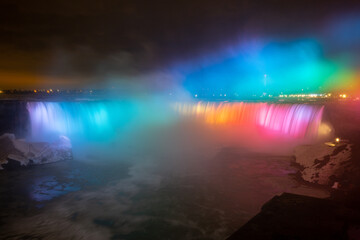 Night illumination on Horseshoe Falls at Niagara Falls Canada are pouring water through frozen landscape at winter