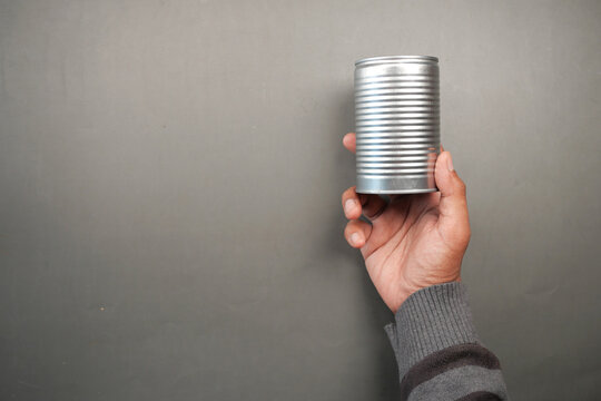 Man Holding A Canned Food On Black Background 