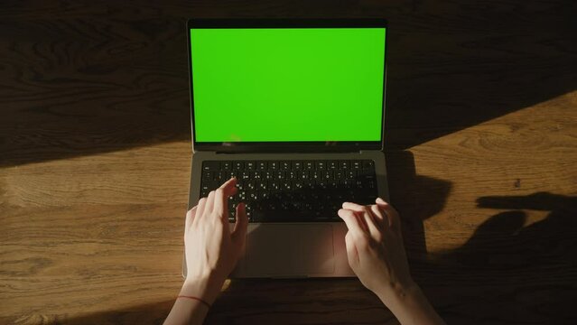 Top view of a caucasian woman hands typing code and hold still on laptop computer with green screen