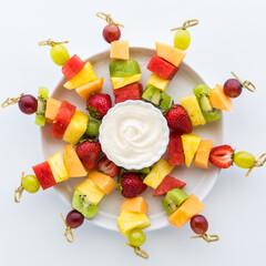 A platter of fresh fruit skewers isolated against a white background. 