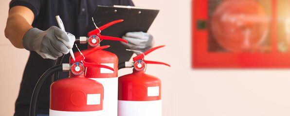 Close up fire extinguisher and firefighter checking pressure gauge level for protection and prevent...