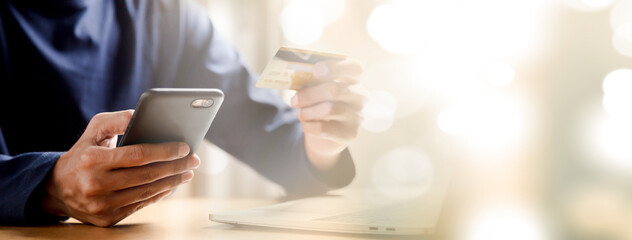 Man holding credit card and using smartphone at home online shopping ecommerce internet banking spend money work from home concept.