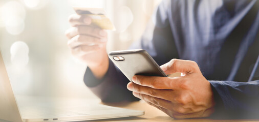 Man holding credit card and using smartphone at home online shopping ecommerce internet banking spend money work from home concept.