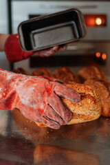 baker takes out freshly baked bread from the mold