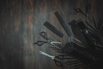 Scissors, combs, shampoo and men's hair clipper lie on the right on a black