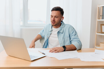 Fototapeta premium Smiling happy friendly good-looking young businessman conducts a job interview remotely using laptop in office. Copy space for ad. Remote Job, Technology And Career Profession Concept
