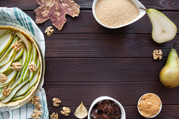 Pear pie tart ingredients frame on brown rustic table, top view. Copy space for text, free space for text.  