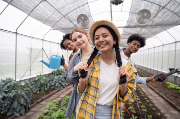 Mix race teenagers holding farmer tool in organic greenhouse	