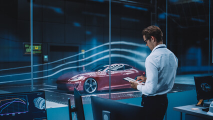 Engineering Research Agency Perform Aerodynamic Testing with a Modern Eco-Friendly Electric Sports Car in a Wind Tunnel. Professional Scientist Works on a Tablet Computer and Changes Testing Options. - obrazy, fototapety, plakaty