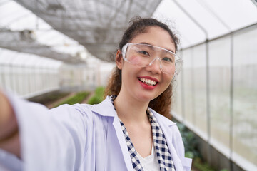 Pretty female scientist take a selfie on mobile in greenhouse organic farm