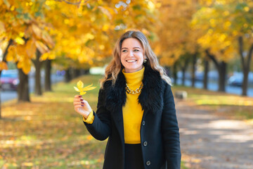 laughing beautiful girl in autumn park. young woman with falling chestnut leaves. lady in the fall. portrait happy smiling female looking at camera