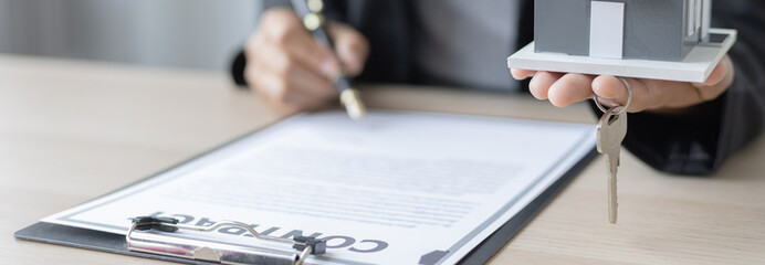 Sales manager or salesperson holds a demo house and has a home purchase contract with keys to...