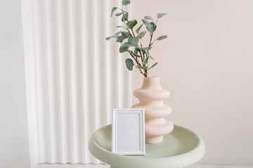 Photo frame mockup on table with vase with eucalyptus branches