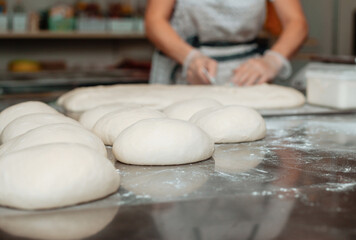 baker shaping bread raw dough before baking on the table in bakery