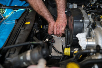 Car mechanic hands replacing intercooler on a car engine. Mechanics workshop.