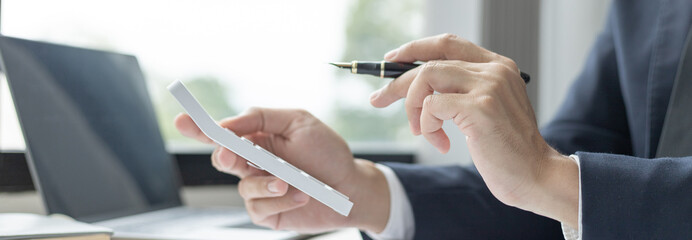 Businessman presses a calculator to calculate earnings and analyze company earnings in his private office, Information in finance and accounting, Company performance and revenue.