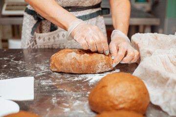 baker shaping bread raw dough before baking on the table in bakery