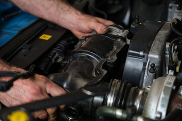 Car mechanic hands replacing engine throttle body. Mechanics workshop.