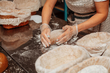 baker shaping bread raw dough before baking on the table in bakery