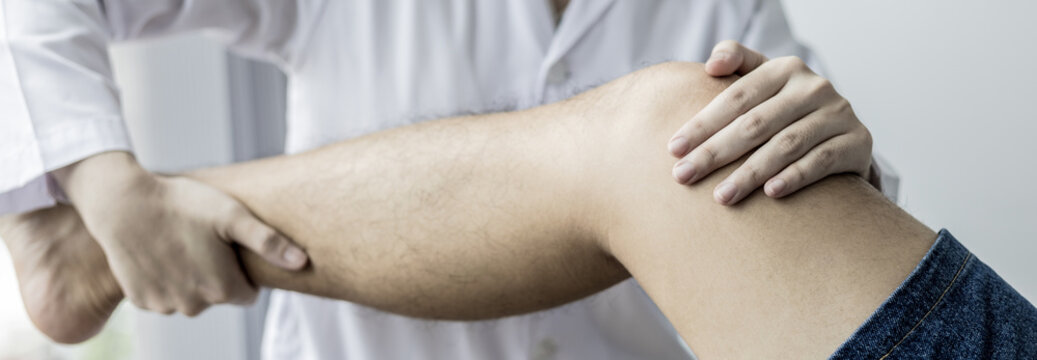 Physical therapy, Female physiotherapist treats legs and hips pain for a male patient attending in clinic, Bone arrangement, Non-surgical medical treatment, Modern medical techniques.