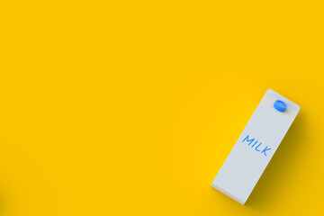 Packaging of milk in corner on orange background. Dairy beverage. Healthy drink. Top view. Copy space. 3d render