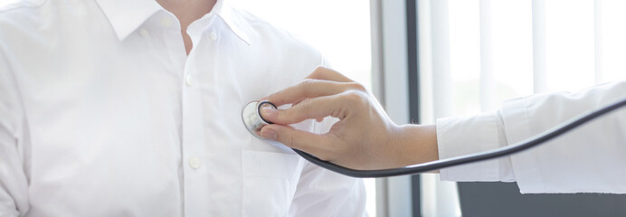 Male doctor uses a stethoscope to measure the patient's heart to check for any abnormalities in his body, Attending an annual health check in a hospital or clinic, Healthcare and medical concept.