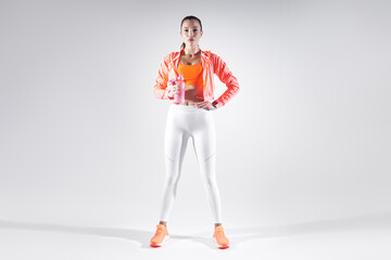Fototapeta na wymiar Full length of beautiful young woman in sports clothing drinking water against white background