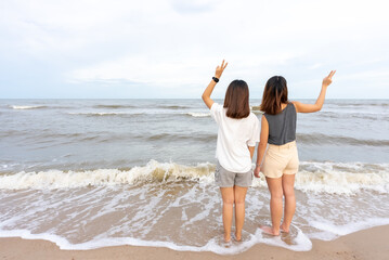 Young couples prefer Asian women who are tourists. walking along the beach which the waves crashed with a cheerful expression on her holiday evening atmosphere sunset
