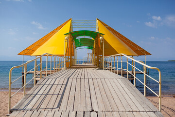 Swimming area or pier on the sea. A large pier with a roof, wooden planks and rusty stairs...