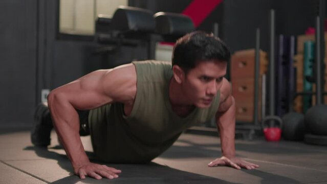 Sport fitness indoor, Handsome young asian athletic man doing push up exercise muscular. Muscular guy strong in sportswear bodybuilding training doing pushup workout on floor at crossfit gym.
