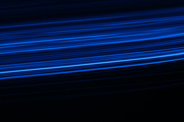 Blur glowing lines. Neon light flare. Futuristic illumination. Defocused UV navy blue color beam trail glare motion on dark black decorative abstract background.