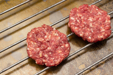 Raw beef burgers on grill.