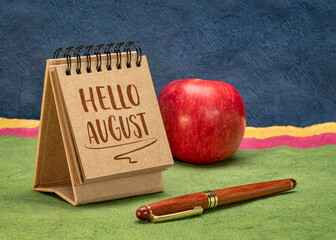 Hello August greeting note  - handwriting in a small desktop calendar against colorful abstract paper landscape