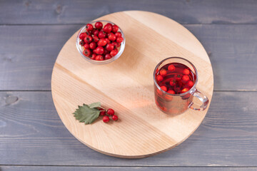 glass of hawthorn juice and fresh hawthorn berries on a wooden board, top view
