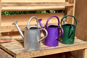 watering cans in shed with a wooden background