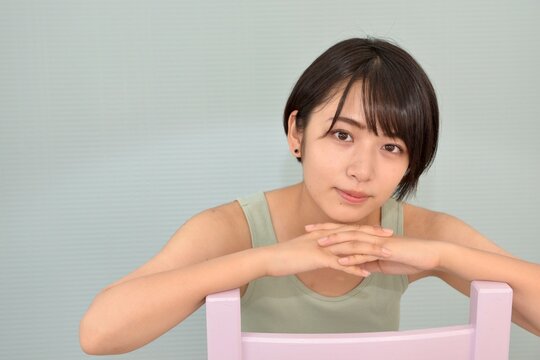 椅子に座り微笑むキャミソールを着た若い女性のポートレート