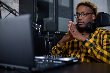 Young African man, a professional music producer, composer, sound engineer, arranger working in a home recording studio. The concept of postproduction and broadcasting - obrazy, fototapety, plakaty