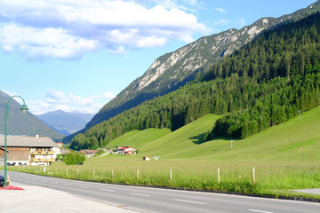 Pertisau resort, hotels and guest houses for vacationers, green mountains rise along the highway,...