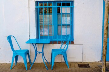 Fototapeta na wymiar Two blue chairs and a table on the terrace of a restaunte in a typical Mediterranean village