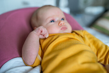 A charming newborn baby with blonde hair and blue eyes lies in a cocoon