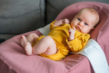 A charming newborn baby with blonde hair and blue eyes lies in a cocoon
