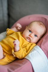 A charming newborn baby with blonde hair and blue eyes lies in a cocoon