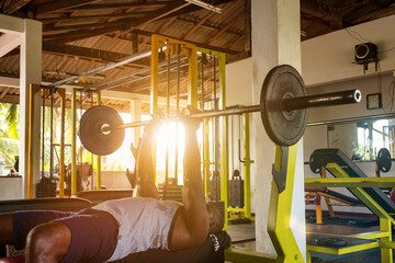 Sri Lankan bodybuilder man lifting barbell at old gym. Sportsman doing exercises with barbells