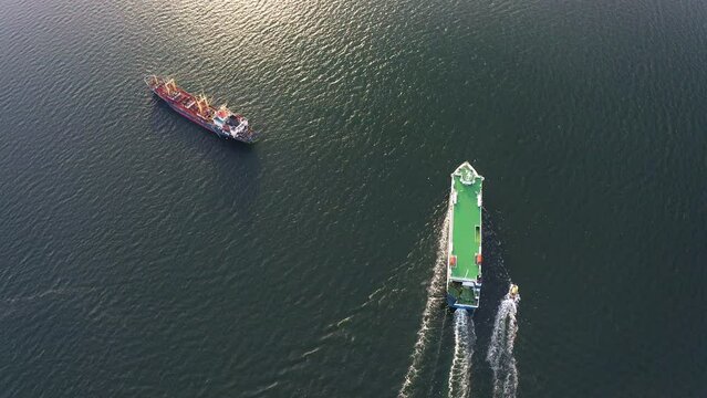 Large car ferry RoRo with a pilot boat - transportation of cars and passengers, cruising the East Sea. Sea ferry transportation. View from the drone vertically down
